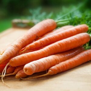 A bunch of fresh organic carrots on a wooden surface, perfect for healthy cooking.